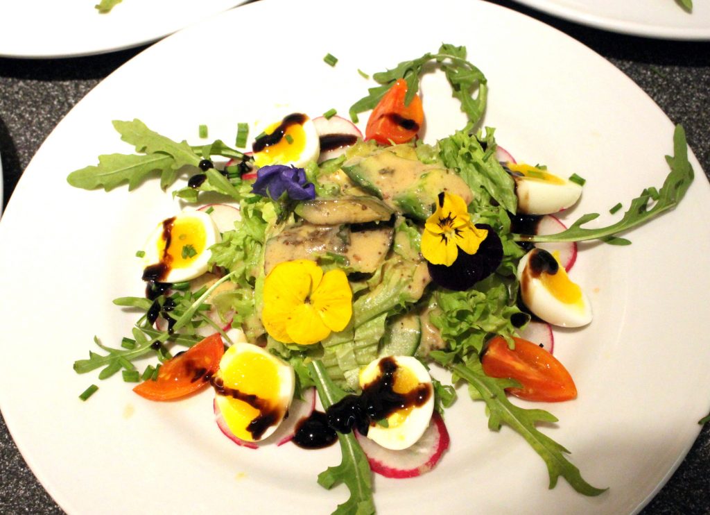 Schoener Salat mit essbaren Blumen und Sesam Dressing