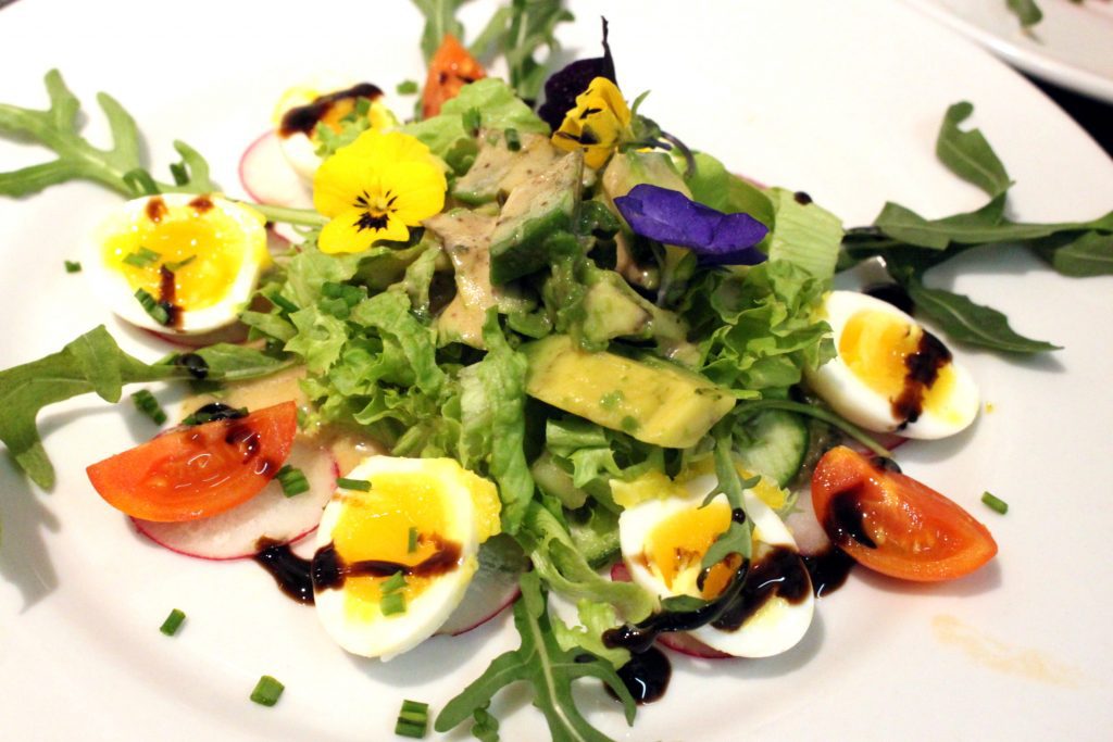 Schoener Salat mit essbaren Blumen und Sesam Dressing