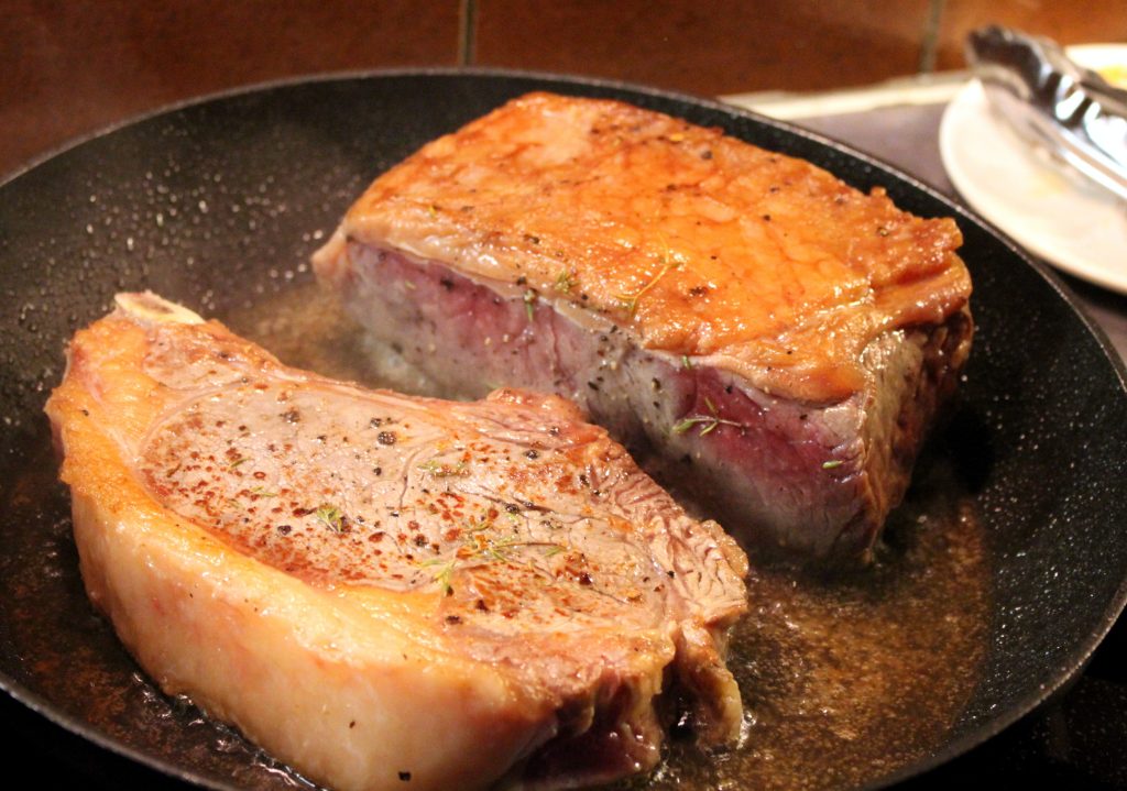 Entrecote und Rindersteak mit Knochen in der Pfanne gebraten